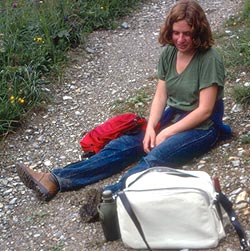 tired girl sitting on foot path, bags around her